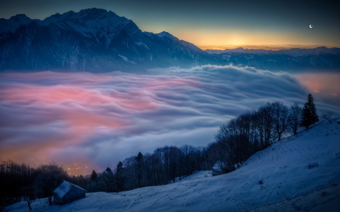 Mountain range above clouds at sunset with moon