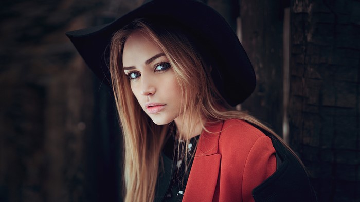 Woman with blonde hair wearing a black hat and red jacket
