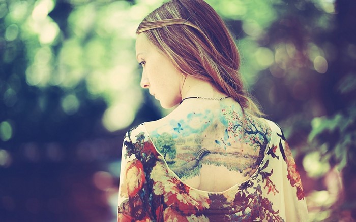 Woman with a large back tattoo of a landscape