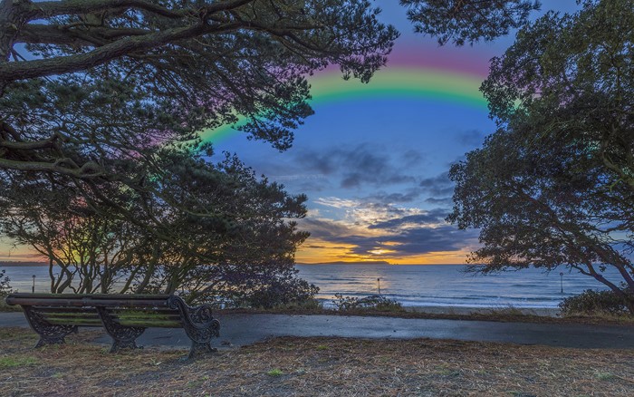 Bench by the sea with a rainbow