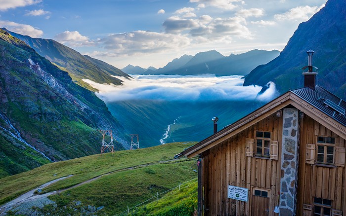 Mountain valley with clouds and a wooden hut