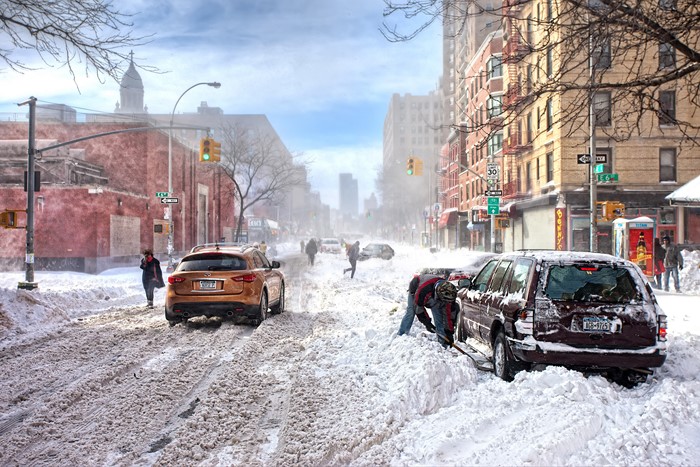 People and cars in a snowy city street during winter