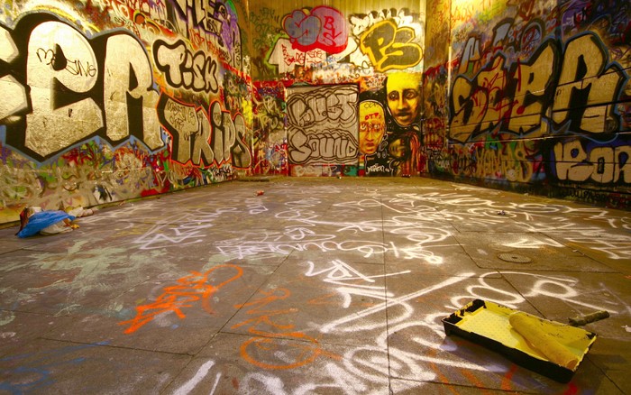 Graffiti-covered urban underpass with paint supplies