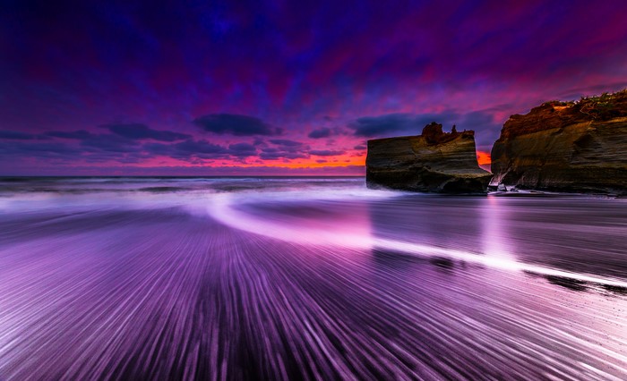 Purple Sunset Over Ocean With Rocks