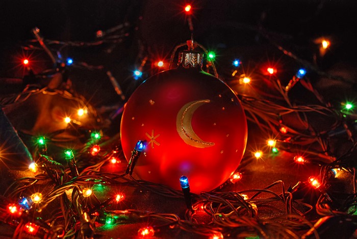 Red Christmas ornament with moon and stars surrounded by lights