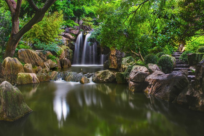Waterfall in a rocky forest park with stone stairs