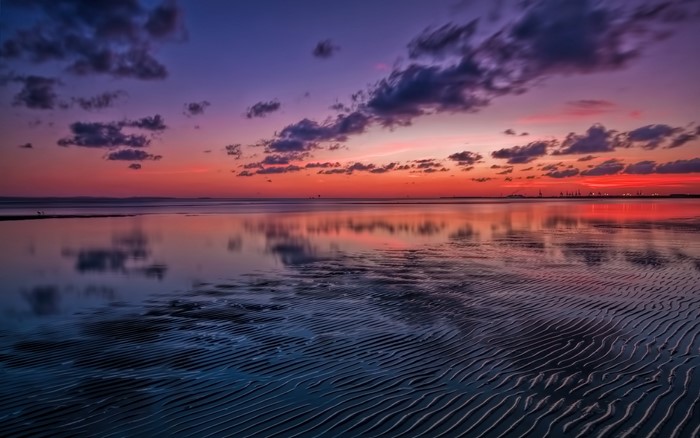 Sunset over the ocean with rippled sand