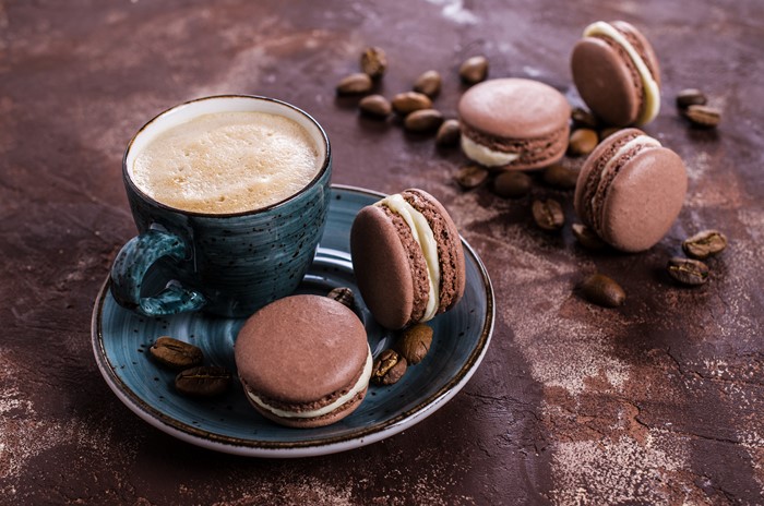 Coffee cup with macarons and coffee beans