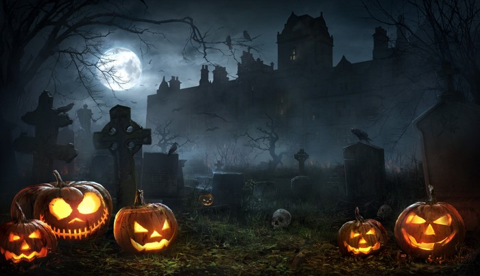Halloween graveyard with jack-o'-lanterns and a haunted house