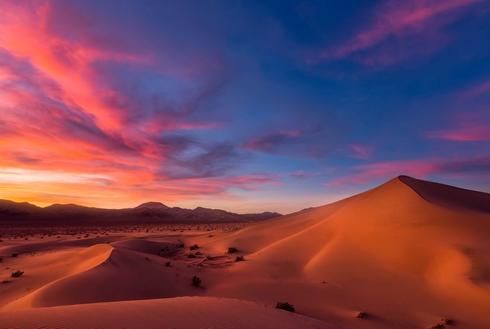 Desert dunes at sunset with colorful sky