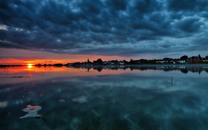 Sunset over a coastal town with dark clouds