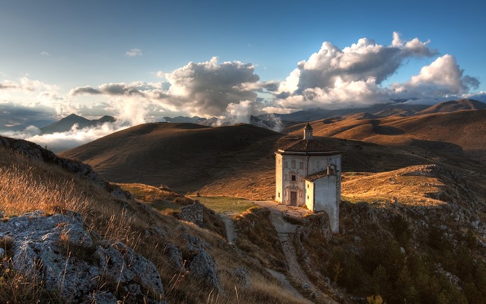 Octagonal church on a grassy hill at sunset
