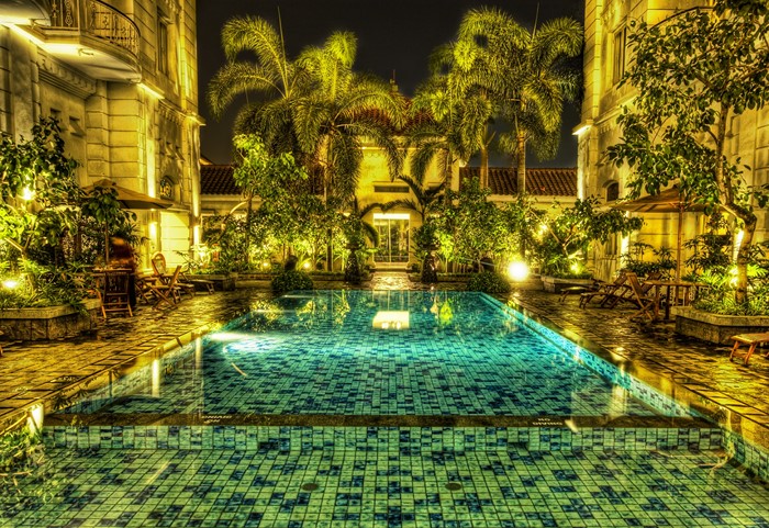 Swimming pool with palm trees and building at night