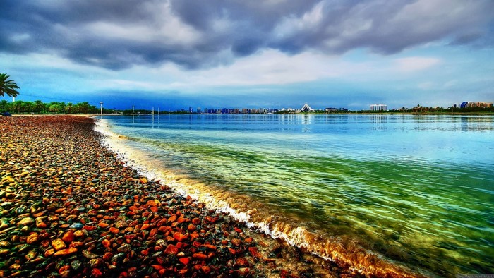 Pebble Beach with City Skyline and Stormy Sky