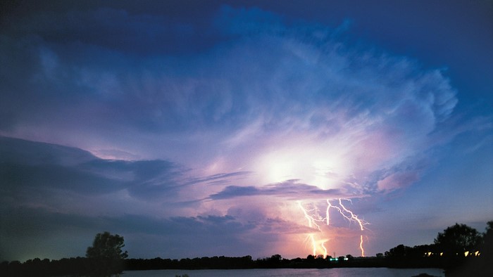 Lightning strikes over a lake at dusk