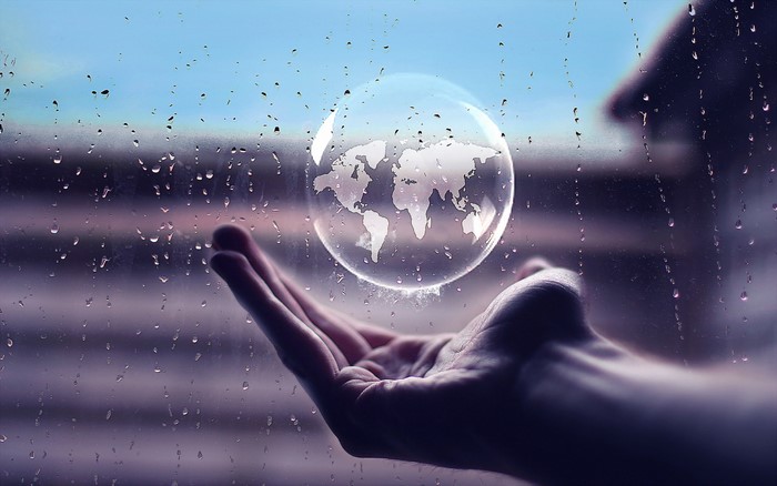World map in a bubble held by a hand