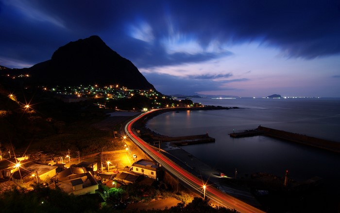 Coastal town at night with mountain and sea