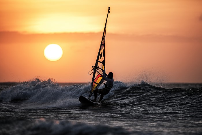 Windsurfer silhouetted against a sunset over the ocean