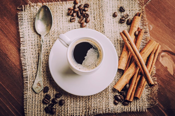 Coffee cup with cinnamon sticks and coffee beans