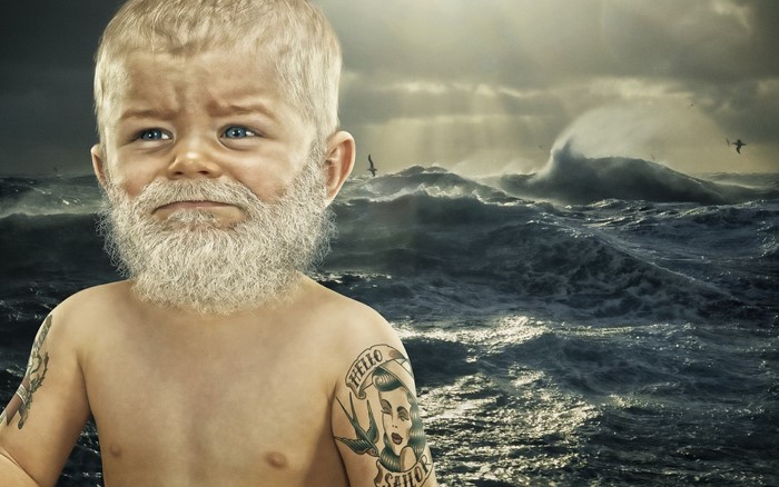 Baby with beard and tattoos in front of stormy sea