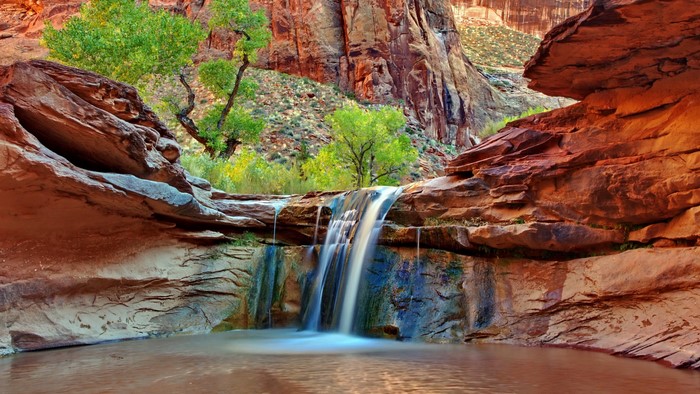 Canyon waterfall with red rocks and green trees