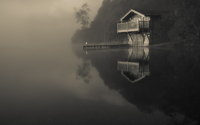 Boathouse on a foggy lake with reflections