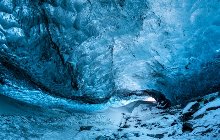 Blue ice cave with snow and rock formations