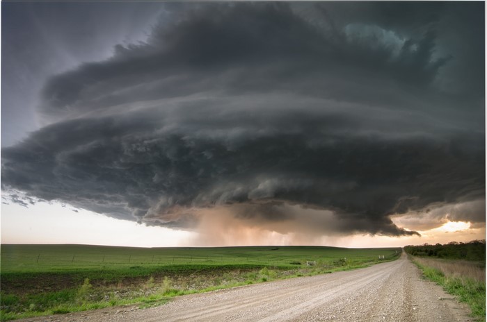 Storm clouds over a rural landscape with a dirt road