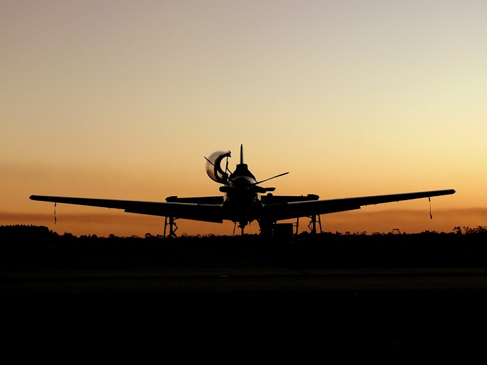 Silhouette of an aircraft on a runway at sunset