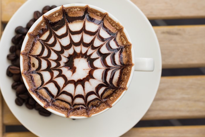 Coffee cup with latte art and coffee beans