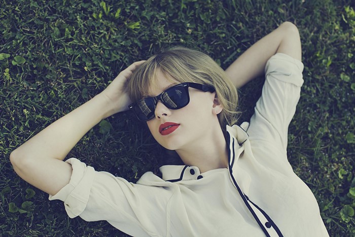 Taylor Swift lying on grass wearing sunglasses