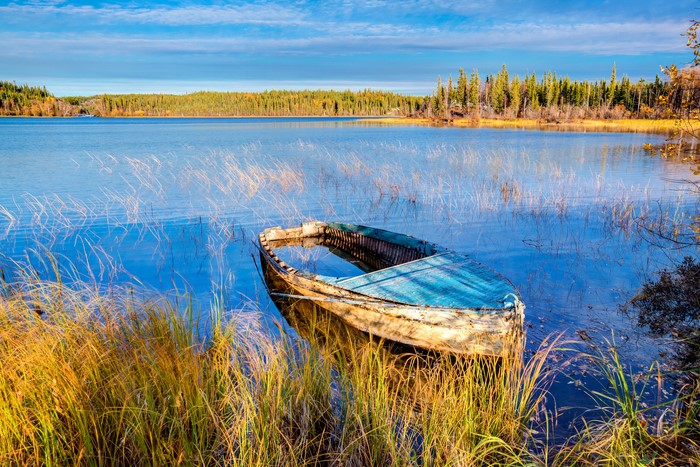 Sunken boat in a lake with autumn trees