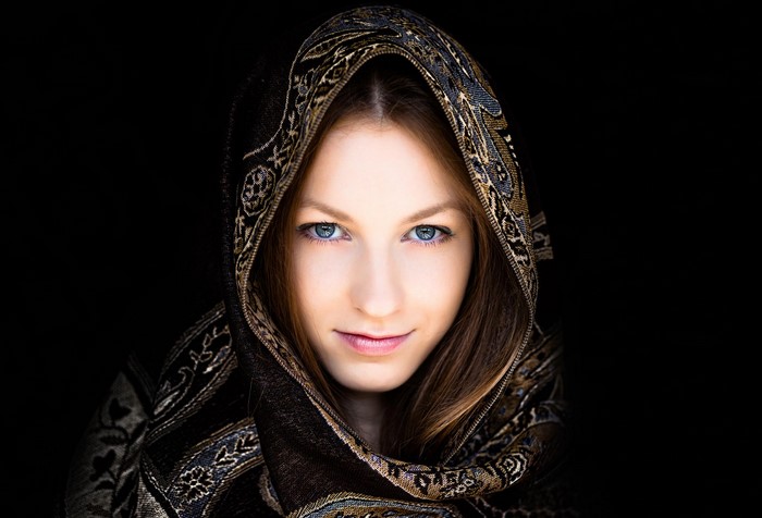 Woman with patterned headscarf against black background