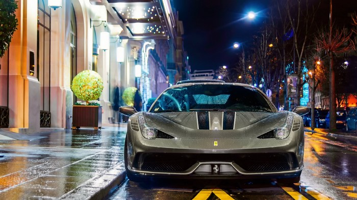 Ferrari parked on a wet street at night