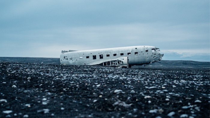 Wrecked airplane on a black sand beach