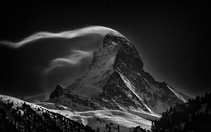 Matterhorn mountain at night with clouds and stars