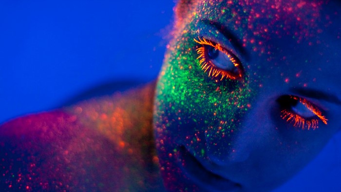 Woman with neon paint under blacklight