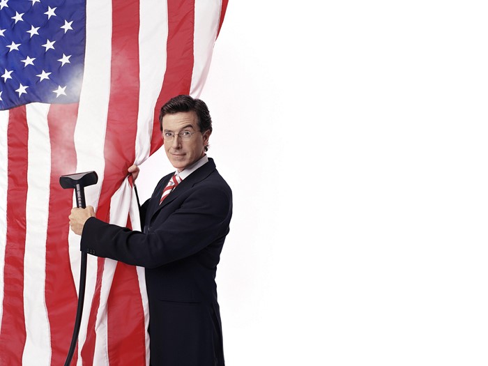Stephen Colbert holding a cane behind American flag