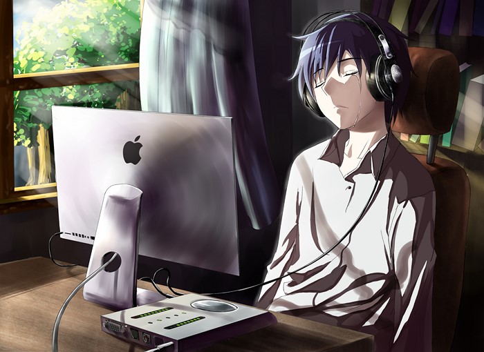 Man wearing headphones and crying in front of Apple computer