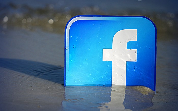 Facebook logo on a beach with water