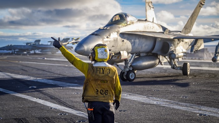 Aircraft carrier deck with F/A-18 Hornet and deck crew