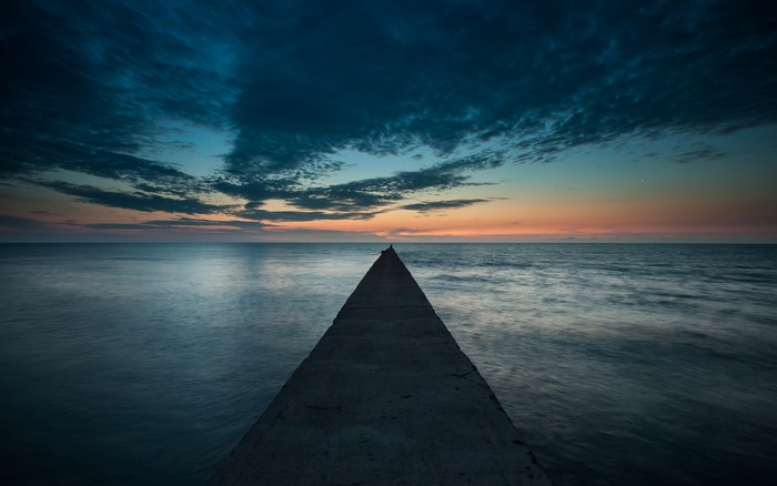 Man on a pier at sunset over the ocean
