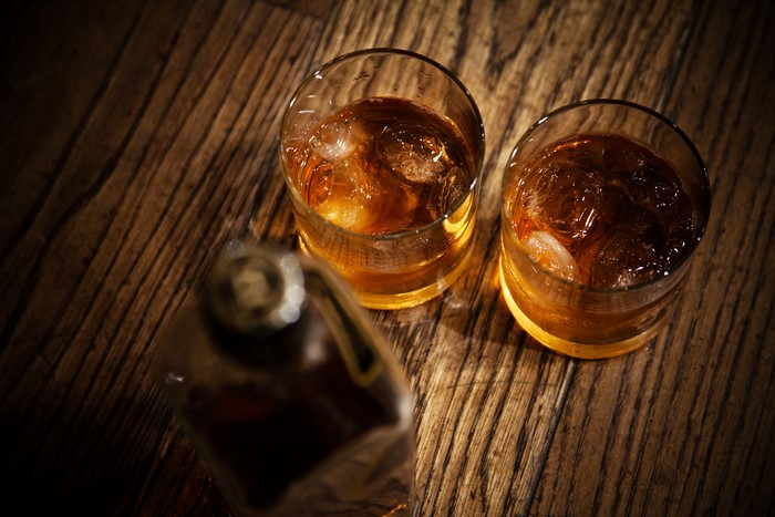 Whiskey glasses and bottle on wooden table