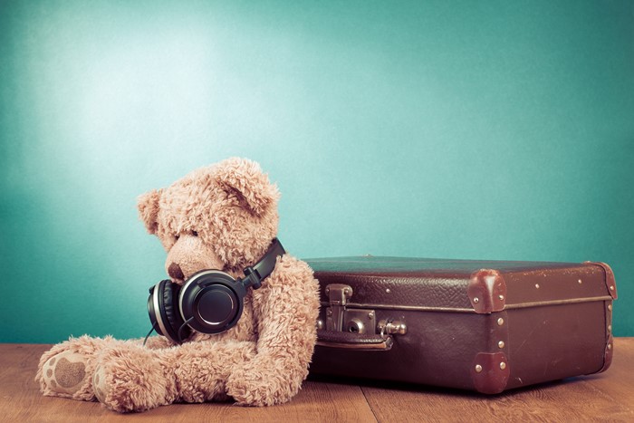 Teddy bear with headphones and suitcase