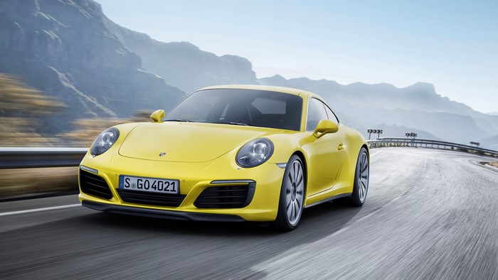 Yellow Porsche 911 Carrera driving on a mountain road