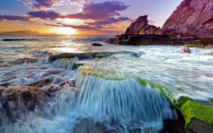 Ocean waves crashing on rocks at sunset