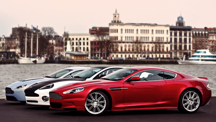 Aston Martin cars parked by a waterfront with buildings