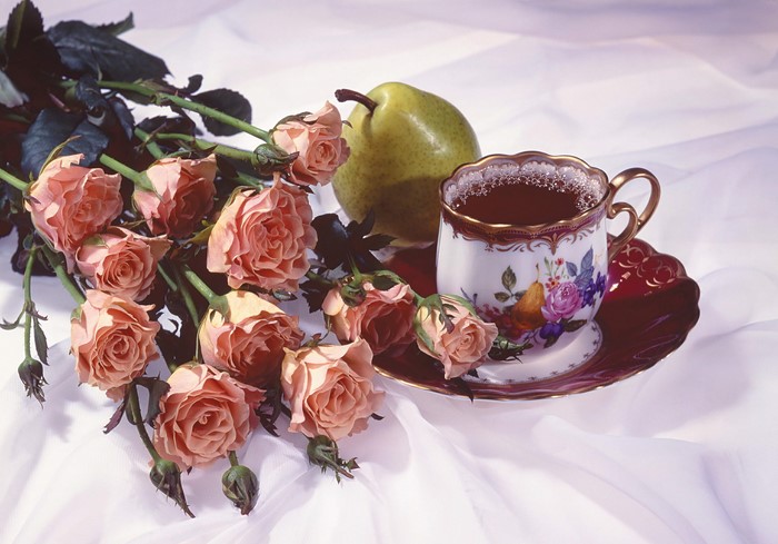 Pink roses, pear, and tea cup on white fabric