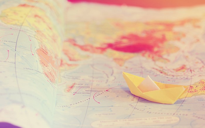 Yellow paper boat on a world map