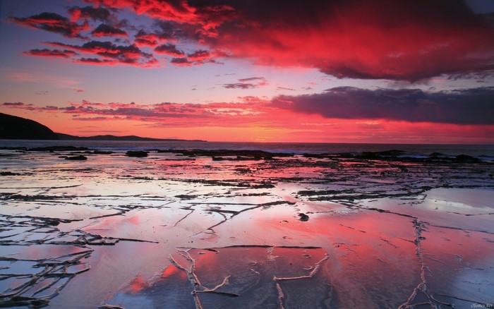 Sunset over rocky shore with red clouds